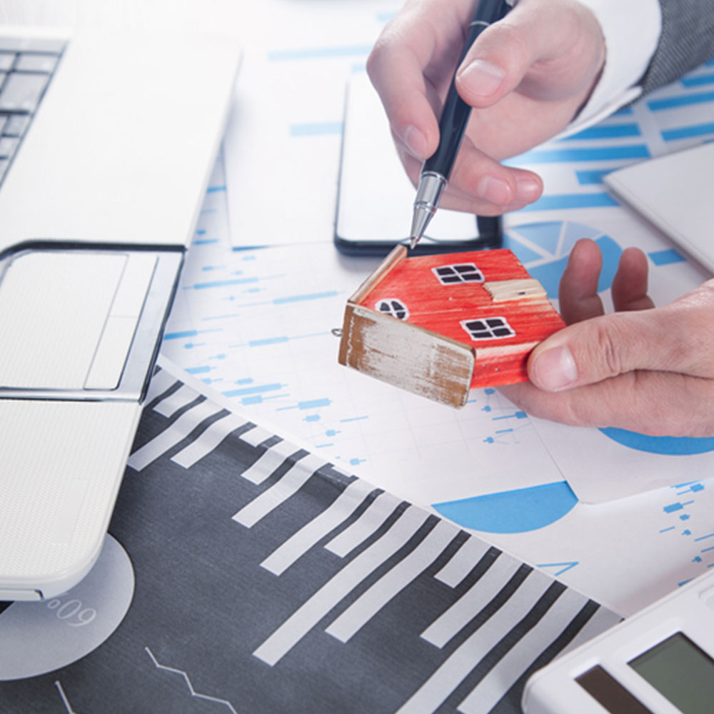 Man holding house model and calculating the process of bridging loan