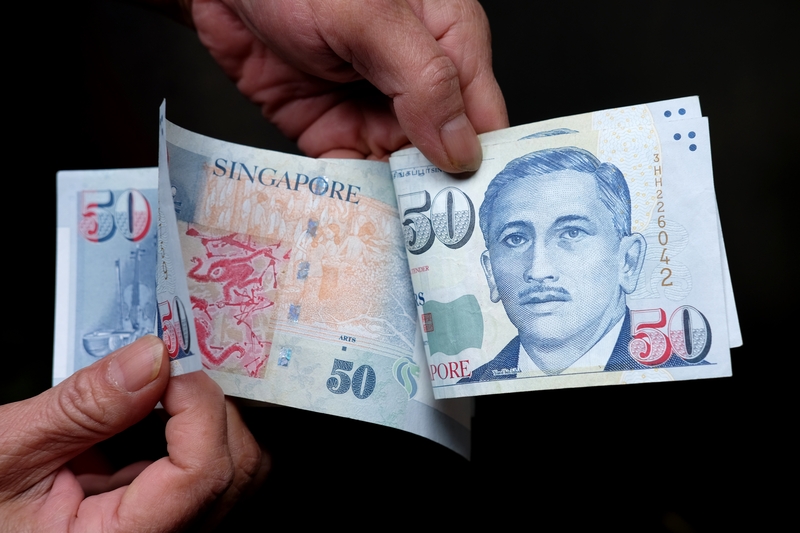 Individual counting 50 Singapore Dollar notes, representing how to deal with loan sharks in Singapore