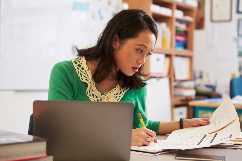 School teacher at her desk marking students’ papers